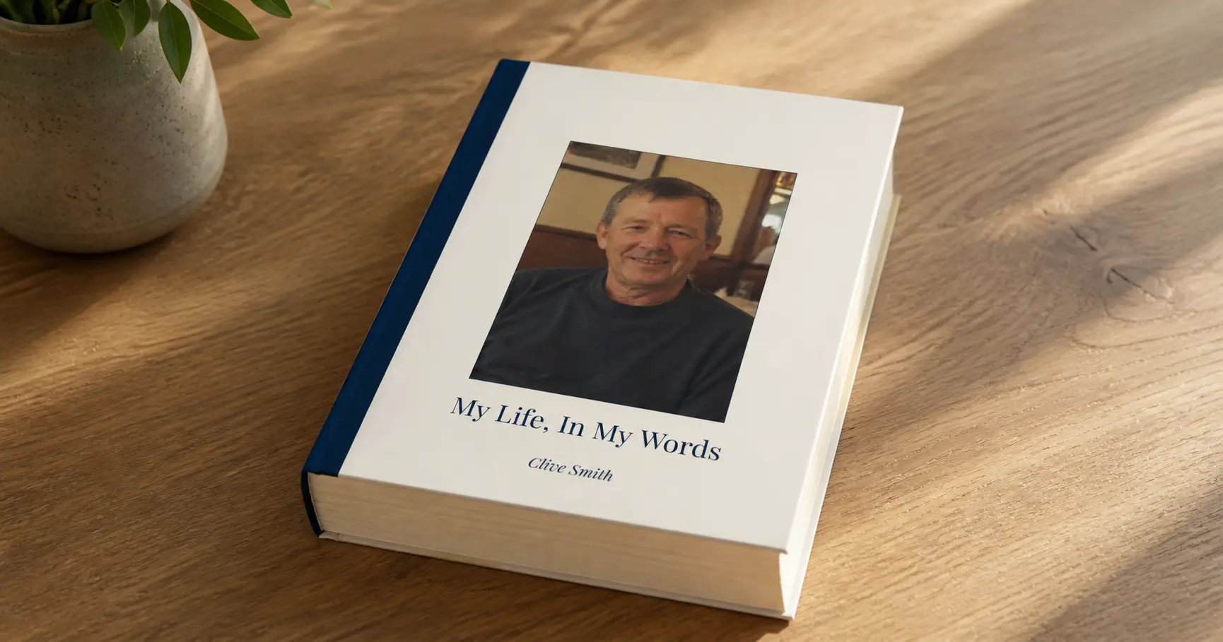 Biography Studio hardback book on a wooden table beside a plant